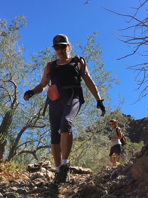 Two hikers climbing through a boulder gap using a rope on a Loreto canyon hike