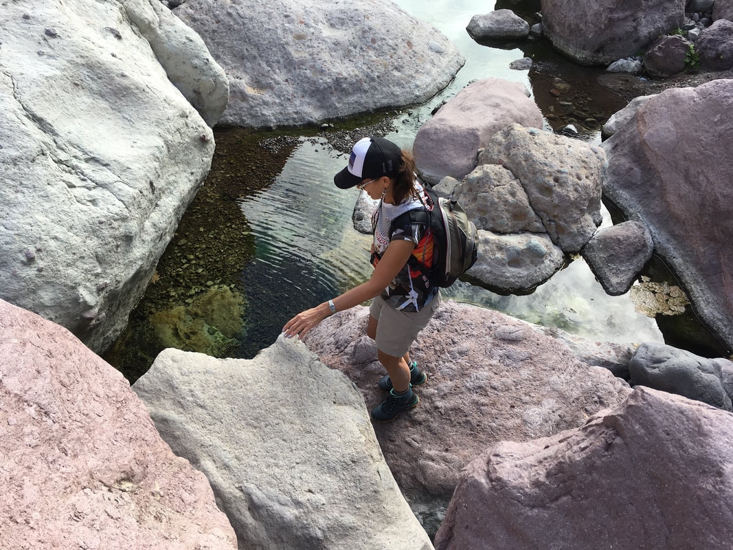 Hiker resting beside a clear river pool in a lush Baja canyon near Loreto