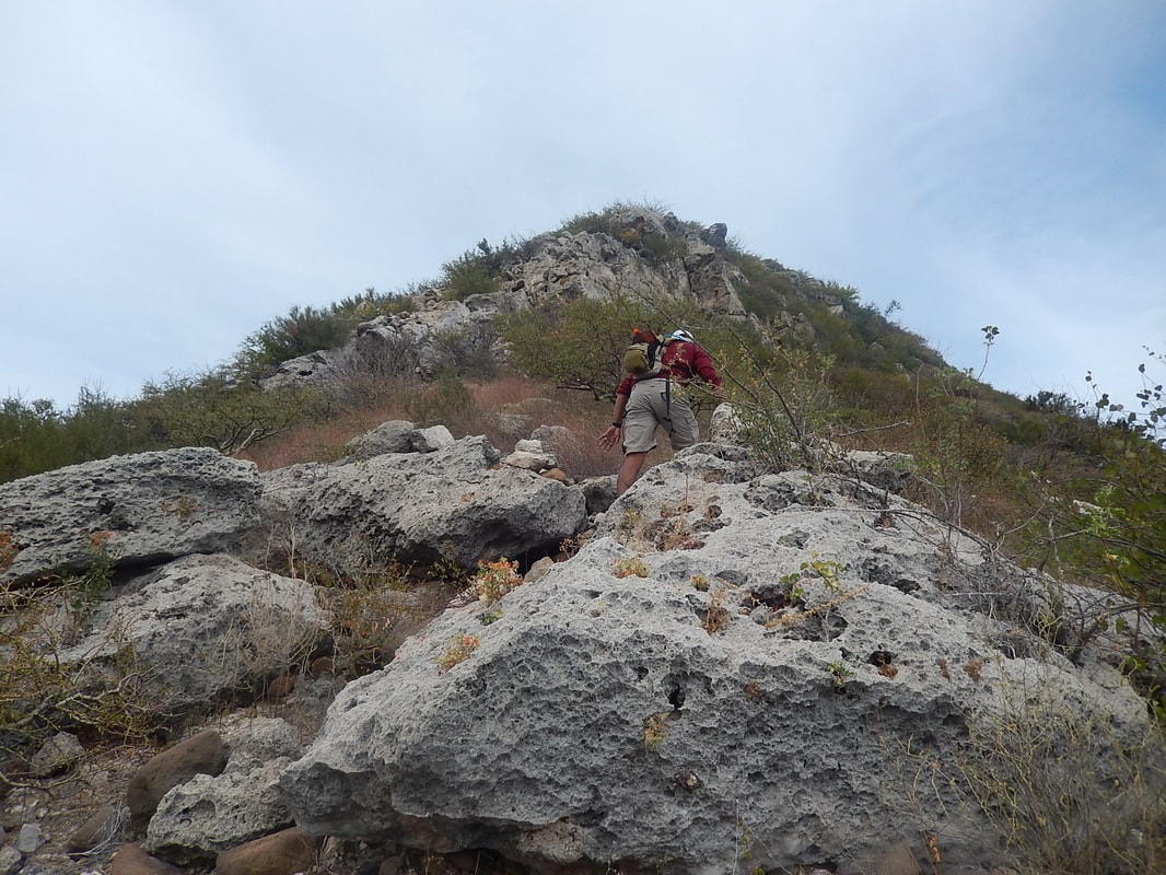 Hiker wading through a rocky canyon stream in the Sierra de la Giganta near Loreto