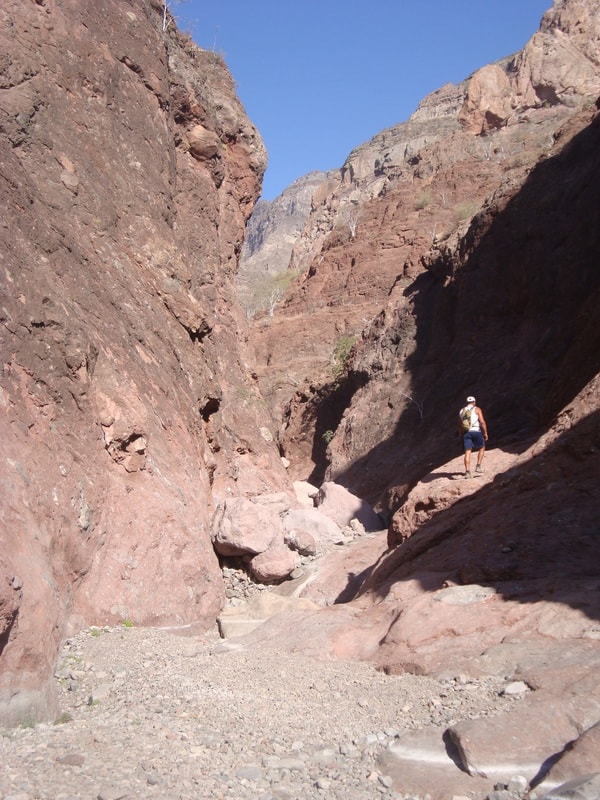Group of hikers posing between giant boulders in a canyon near Loreto