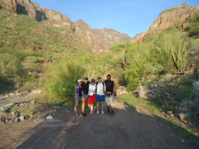 Group exploring a rocky canyon with a natural rock arch in the Sierra de la Giganta