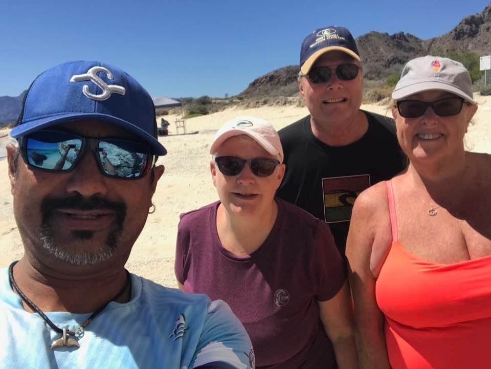 Guide and three guests smiling in a selfie on a sunny Loreto island beach
