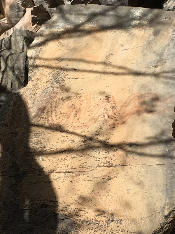 Ancient cave paintings with faded ochre figures on stone near Mission San Javier